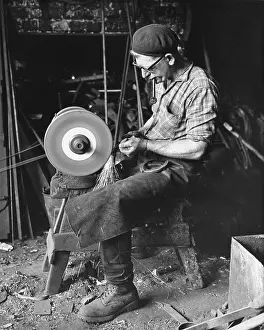 Farrier: A Farrier grinding down a horseshoe