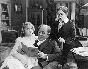 Sneaking: Father reading to his daughter while his son is