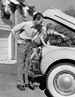 Whitewall: Father & son checking under hood of car in driveway
