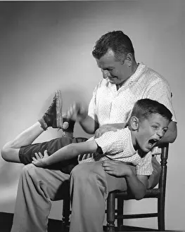 Spanking: Father with son over his lap while getting a spanking