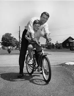Camerique: Father stopping to pose with son while teaching him to ride