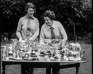 Trophies: Two Female Civilians Standing Behind A Table