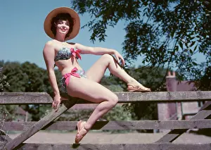 Sunhats: Female model in a bikini, sitting on a gate