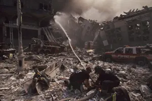 Nyfd: Fire fighters set up a hose amid smoking rubble