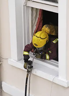 Windowsill: Firefighter using a rope to pull a hose up a building