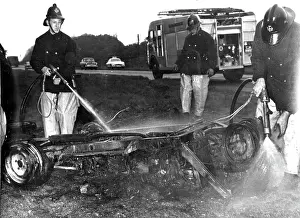 Charred: Firefighters hosing down a burnt-out car