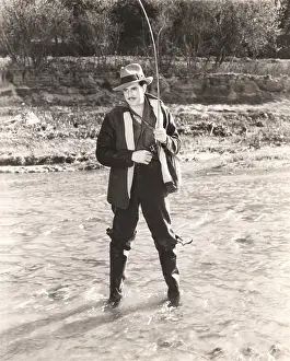 Fedora: Fisherman in waders fishing in river