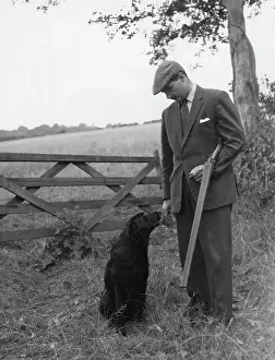 Gamekeeper: Gamekeeper and dog standing near five-bar gate