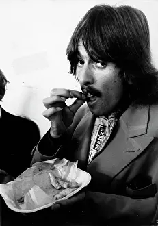 Sitarist: George Harrison of The Beatles pop group eating chips