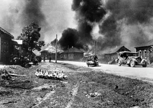 Transition: German motorcycle troops cross a burning village on the