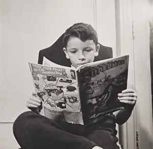 German refugee boy reading a Superman comic at