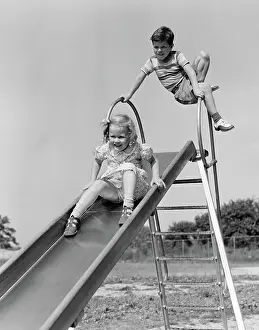 Lofty: Girl going down slide boy waiting at top