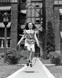 Cardiovascular: Girl Jumping Rope on Sidewalk Looking at Camera