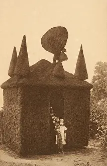 Clipped: Girl stood by intricate topiary house