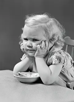 Disgruntled: Girl at table with head cradled in both hands