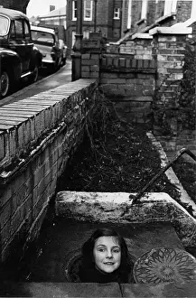 Grating: Girl's head emerging from a coal hole