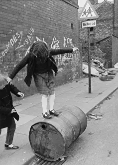 Balancing: Two girls playing with an oil drum