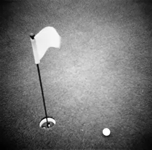 Tch001: GOLF BALL ON PUTTING GREEN WITH FLAG MARKER IN