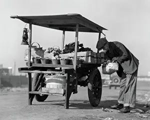 Greengrocer: Grocer outdoors at vegetable cart