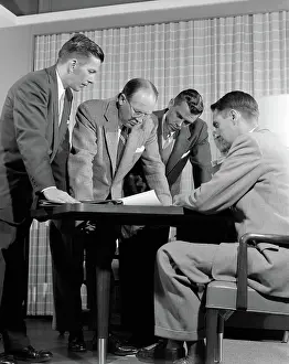 Businesspeople: Group of men businessmen looking at plan on desktop