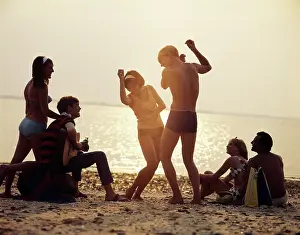1960ss: Group of Young Couples Playing Guitar and Dancing Sunset B