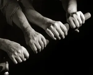 Propelling: Four Hands of Two Men Rowing Pulling on An Oar Together