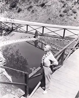 Contentment: High angle view of man standing on bridge overlooking pond