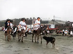 Holidaymakers riding donkeys on a beach