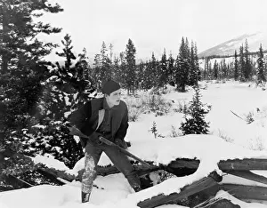 Aloneness: Hunter with his rifle walking through snow covered
