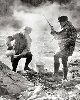 Macho: Two Hunters Standing Camped by Stream One Making
