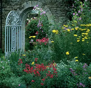Faringdon: Iron gate in a stone wall with Summer flowers