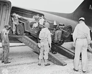 Freight: A jeep is being loaded into a plane, circa 1942