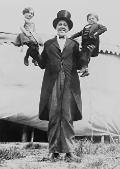 Gigantism: Johan John Aasen holding a midget, in each hand