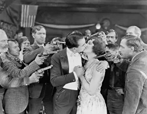 Gangs: Kissing couple surrounded by men with guns