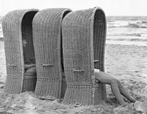 Basketwork: Three large woven beach chairs at the seaside