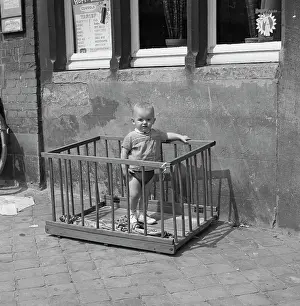 Tony Boxallfrps: Little boy standing in a playpen on a pavement