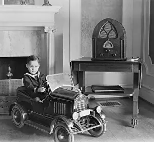 1 Person: Little boy in his toy automobile next to a state