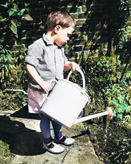 Helpful: Little boy watering the garden
