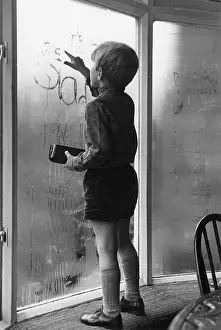 Condensation: Little boy writing on a condensated window