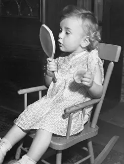 Fascinated: Little girl looking in mirror
