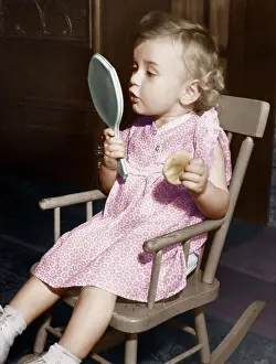 Fascinated: Little girl looking in mirror