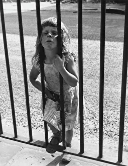Little girl looking through railings