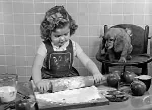 Highchair: Little girl rolling out apple pie crust on kitchen