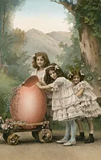 Wheeling: Three little girls with a large Easter egg on a trolley