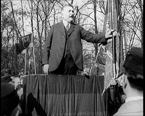 Pendants: A Male Civilian Makes a Speech from a Stand