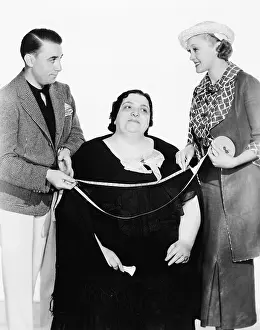 Aides: Male tailor and his assistant measuring an overweight