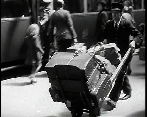 Suitcases: A Male Train Station Porter Pushing a Sack