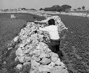 Man aiming rifle from behind a stone wall