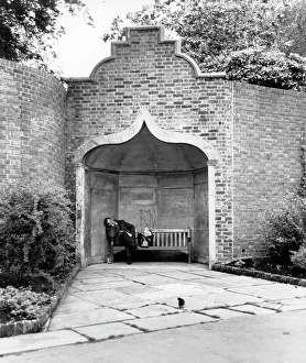 Cowan: Man asleep on a bench in an alcove in a park