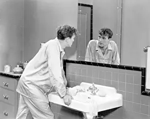 Washbasin: Man in bathroom looking into mirror